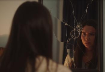 Actress Sera-Lys McArthur looks into a broken mirror