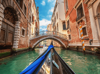 A gondola moves along a canel among historic buildings.