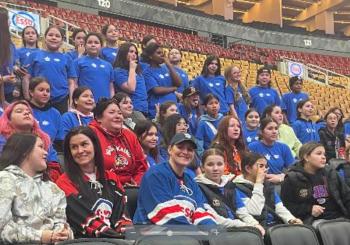 First Nations girls in te arena stands get photographed with a hockey legend.