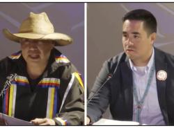 Two men: At left is a man wearing a ribbon shirt and a straw hat. At right is a man in a suit.