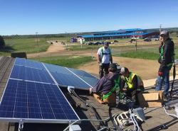 People are working on a rooftop installing solar panels.