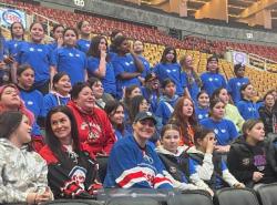 First Nations girls in te arena stands get photographed with a hockey legend.