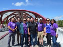 A group of smiling people stand on a bridge over a river for the photo.
